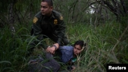 Seorang petugas perbatasan AS menangkap perempuan yang berusaha masuk AS secara ilegal dekat perbatasan Meksiko di McAllen, Texas, 2 Mei 2018. 