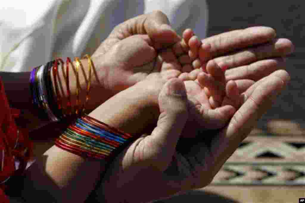 A Pakistani mother helps her daughter to pray on the Eid-al-Adha festival in Lahore, Pakistan Monday, Nov 7, 2011. Pakistani Muslims celebrated Eid al-Adha, or the Feast of the Sacrifice by slaughtering of sheep, goats, cows or camels. (AP Photo/K.M.Chaud