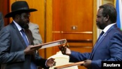 South Sudan's rebel leader Riek Machar (R) and South Sudan's President Salva Kiir (L) exchange signed peace agreement documents in Addis Ababa, Ethiopia, May 9, 2014.