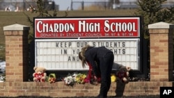 A female student places a bouquet of roses at the base of the Chardon High School sign in Chardon, Ohio February 28, 2012.
