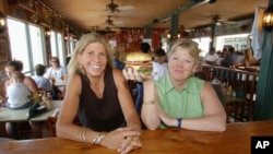 FILE - Cheeseburger in Paradise founders and co-owners Edna Bayliff, left, and Laren Gartner pose with one of their trademark burgers at their Lahaina, Hawaii, restaurant.