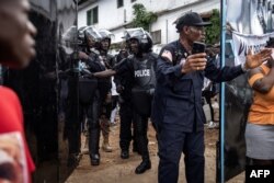 FILE - Liberia police officers control voters waiting outside a polling station in the infamous West Point slum on October 10, 2023 in Monrovia.