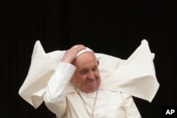 FILE—Pope Francis holds his skull cap to prevent it blowing in the wind, from the central balcony of the St. Peter's Basilica prior to the 'Urbi et Orbi' (To the city and to the world) blessing, at the Vatican, March 31, 2024