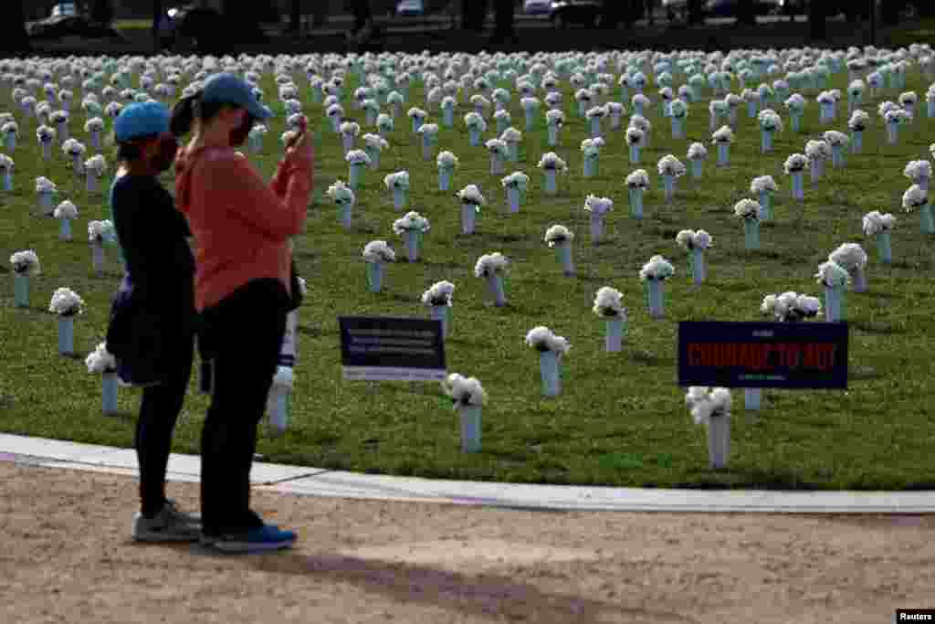 Visitors take pictures of the new Gun Violence Memorial, an installation featuring 38,000 silk white roses in 4,000 vases to commemorate the roughly 40,000 Americans who die annually in gun violence, on the National Mall in Washington.