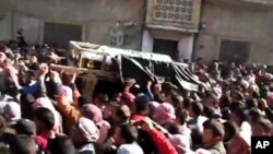 In this image from TV shown on the internet made available by the Sham News Network, protesters carry the body of Tamer Mutlaq in Homs, Syria, December 20, 2011.