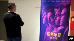 A customer looks at a movie poster for the film "Bohemian Rhapsody" at a movie theater in Beijing, March 27, 2019. 