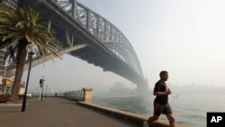 A man jogs under the Sydney Harbour Bridge as a smoke haze hangs over Sydney, Nov. 21, 2019. The annual Australian fire season, which peaks during the Southern Hemisphere summer, has started early after an unusually warm and dry winter. 