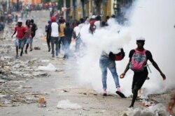 People clash with security forces during a protest to demand the resignation of Haitian President Jovenel Moise, in Port-au-Prince, Haiti, Sept. 30, 2019.