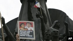 A protester displays a placard with photos of the late Ferdinand Marcos and his wife Imelda at the People Power Monument opposing the proposal to bury the late dictator at the Heroes Cemetery, June 18, 2011, in suburban Quezon City, north of Manila