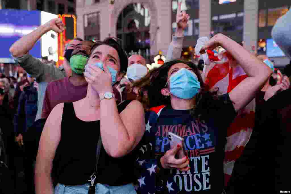 People react as they watch a speech by Democratic 2020 U.S. presidential nominee Joe Biden after news media announced that he has won the 2020 U.S. presidential election, on Times Square in New York.