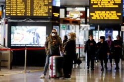 FILE - Travelers wear face masks as they wait at the Termini train station in Rome, March 8, 2020.