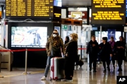 FILE - Travelers wear face masks as they wait at the Termini train station in Rome, March 8, 2020.