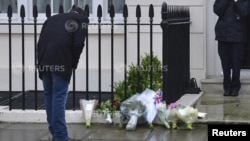 A man looks at floral tributes and messages left outside the home of former British prime minister Margaret Thatcher in London, April 9, 2013. 