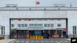 (FILE) Police officers stand at the outer entrance of a detention center in China's Xinjiang Uyghur Autonomous Region.