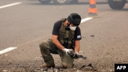 A member of Israeli security forces inspects the impact site of a reported rocket fired from Lebanon, on the Horeshim interchange in central Israel on October 1, 2024.