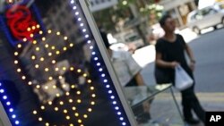 Pedestrians walk past a money exchange outlet in Hong Kong on August 6, 2011.