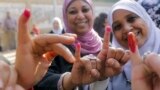 Women show their inked fingers after casting their votes at a polling station in Cairo. Egyptians are voting on a draft for their country&#39;s new constitution.