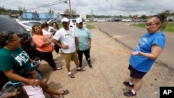 Gabriela Rosales, right, confers with friends outside the employee entrance to the Koch Foods Inc., plant in Morton, Miss., Aug. 8, 2019, that was raided Wednesday by U.S. immigration officials.