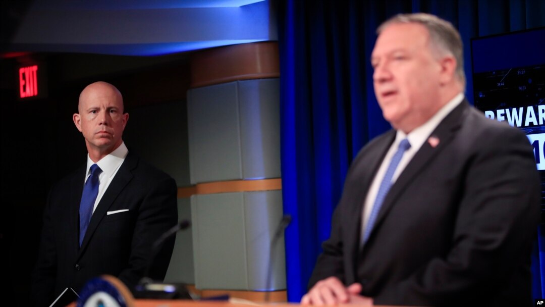 State Department Deputy Spokesperson Cale Brown, left, listens to Secretary of State Mike Pompeo, right, speak during a news conference at the State Department in Washington, Aug. 5, 2020. 