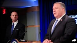 State Department Deputy Spokesperson Cale Brown, left, listens to Secretary of State Mike Pompeo, right, speak during a news conference at the State Department in Washington, Aug. 5, 2020. 