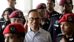 FILE - Deputy Prime Minister and opposition leader Anwar Ibrahim, center, smiles as he arrive at court house in Kuala Lumpur, Malaysia, June 13, 2017.