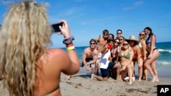 A group of spring break revelers pose for a photograph on the beach, Tuesday, March 17, 2020, in Pompano Beach, Fla.