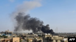 FILE - A smoke plume rises in Tajoura, south of the Libyan capital Tripoli, June 29, 2019, following a reported airstrike.