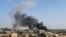 FILE - A smoke plume rises in Tajoura, south of the Libyan capital Tripoli, June 29, 2019, following a reported airstrike.