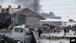 Local residents walk though a devastated street in Tagajo, Miyagi prefecture on March 13, 2011 following a massive earthquake and tsunami on March 11. Japan battled a feared meltdown of two reactors at a quake-hit nuclear plant, as the full horror of the 