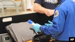 FILE-A Transportation Security Administration (TSA) official checks a passenger's carry-on luggage at a security checkpoint at Hartsfield-Jackson Atlanta International Airport in Atlanta.