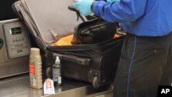 FILE-A Transportation Security Administration (TSA) official checks a passenger's carry-on luggage at a security checkpoint at Hartsfield-Jackson Atlanta International Airport in Atlanta, Aug. 3, 2011.