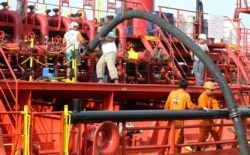 Pekerja memasang pipa untuk memompa minyak sawit mentah (CPO) ke kapal tanker di pelabuhan Belawan di Provinsi Sumatera Utara, 21 Februari 2013. (Foto: REUTERS/Roni Bintang)