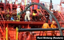 Pekerja memasang pipa untuk memompa minyak sawit mentah (CPO) ke kapal tanker di pelabuhan Belawan di Provinsi Sumatera Utara. (Foto: REUTERS/Roni Bintang)