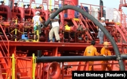 Pekerja memasang pipa untuk memompa minyak sawit mentah (CPO) ke kapal tanker di Pelabuhan Belawan di Provinsi Sumatera Utara, 21 Februari 2013. (Foto: REUTERS/Roni Bintang)