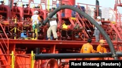 Pekerja memasang pipa untuk memompa minyak sawit mentah (CPO) ke kapal tanker di pelabuhan Belawan di Provinsi Sumatera Utara, 21 Februari 2013. (Foto: REUTERS/Roni Bintang)