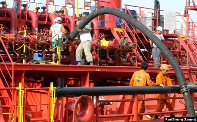 Pekerja memasang pipa untuk memompa minyak sawit mentah (CPO) ke kapal tanker di pelabuhan Belawan di Provinsi Sumatera Utara. (Foto: REUTERS/Roni Bintang)