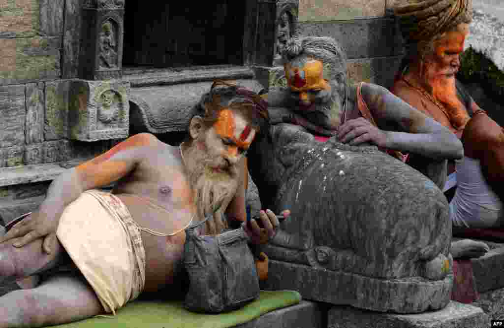 Hindu sadhus - holy men - watches a film on a mobile phone at the Pashupatinath Temple in Kathmandu, Nepal.