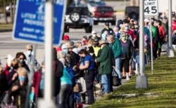 FILE - Hundreds of people wait in line at Lakes Park Regional Library to receive the COVID-19 vaccine in Fort Myers, Florida, Dec. 30, 2020.
