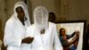 FILE - The wife, Marie-Louise Foe (C), and mother (L), of the late Cameroon player Marc-Vivien Foe, walk past his picture during his funeral ceremony.