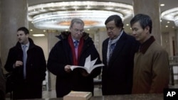 Ketua Dewan Direksi Google, Eric Schmidt (kedua dari kiri), dan mantan gubernur New Mexico Bill Richardson (kedua dari kanan) melihat-lihat buku teks informasi teknologi di Pyongyang, Korea Utara (9/1). (AP/David Guttenfelder)