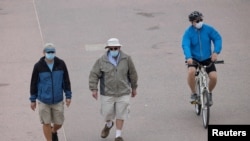 Personas usan tapabocas en un paseo frente a la playa en Huntington Beach, California, el 1 de julio de 2020.