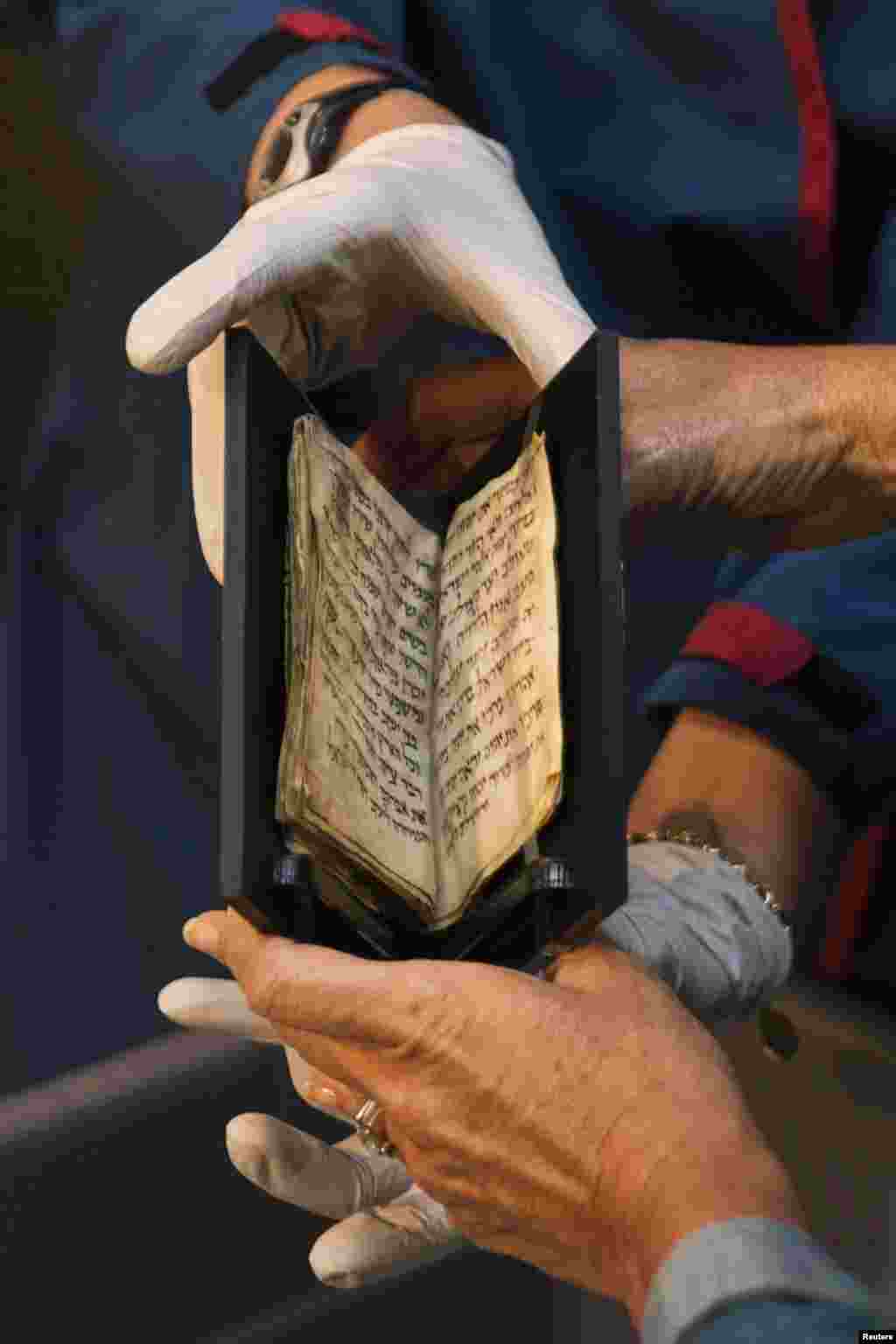 Bible Lands Museum director Amanda Weiss (R) holds an ancient Siddur, or Jewish prayer book, as she puts it on display at the museum in Jerusalem. Dating back some 1,200 years, the ninth century A.D. Siddur is the oldest Jewish prayer book known to exist. Originating in the Middle East, it contains around 50 pages written in Hebrew. 