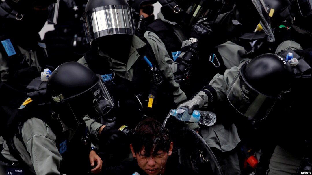 Riot police pour water on the face of an anti-government protester who was pepper sprayed while getting detained after an anti-parallel trading protest at Sheung Shui, a border town in Hong Kong, 