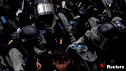 Riot police pour water on the face of an anti-government protester who was pepper sprayed while getting detained after an anti-parallel trading protest at Sheung Shui, a border town in Hong Kong, 