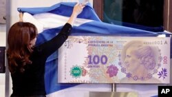 Argentina's president Cristina Fernandez unveils the new 100-peso bill bearing the profile of former first lady Maria Eva Duarte de Peron, better known as "Evita," at government palace in Buenos Aires, July 25, 2012. 