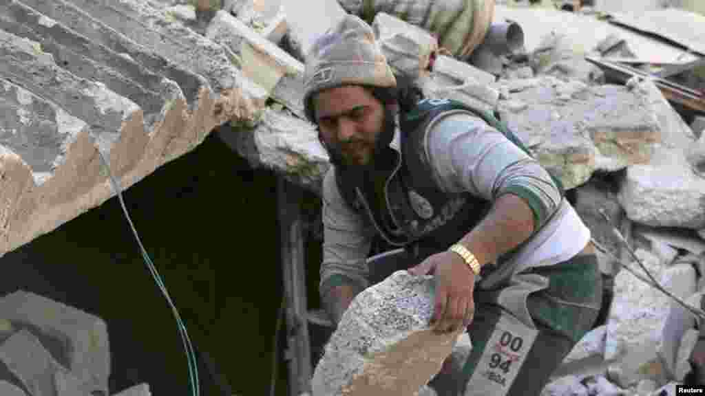 A man removes rubble at a site hit by what activists said was a barrel bomb dropped by forces loyal to Syria's President Bashar al-Assad in the al-Myassar neighborhood of Aleppo, Feb. 12, 2014. 