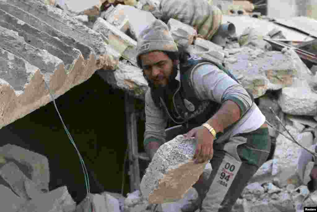 A man removes rubble at a site hit by what activists said was a barrel bomb dropped by forces loyal to Syria's President Bashar al-Assad in the al-Myassar neighborhood of Aleppo, Feb. 12, 2014. 