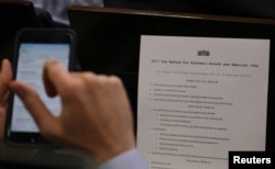 A reporter shoots a picture of a White House press release on its tax reform plan during the daily briefing at the White House in Washington, April 26, 2017.