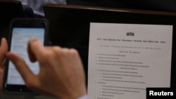 A reporter shoots a picture of a White House press release on its tax reform plan during the daily briefing at the White House in Washington, April 26, 2017.