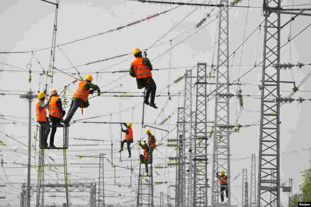 Workers install and adjust overhead power lines at Ankang East railway station in Ankang, Shaanxi province, China, Nov. 22, 2017.